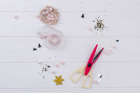 DIY christmas hobby background. String, pearl beads, scissors and sparkling Christmas ornaments on...
