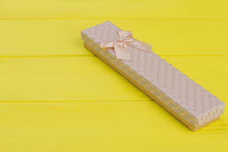 Long fashionable gift box. Yellow wood background.