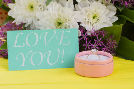 Romantic surprise for Valentine holiday. Gift box with golden ring, fresh flowers and card with...
