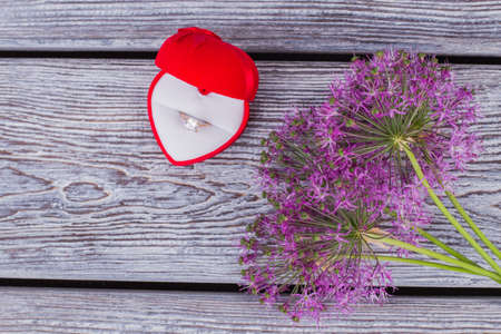 Purple flowers and velvet box with ring. Blooming flowers and red heart shaped box with engagement...