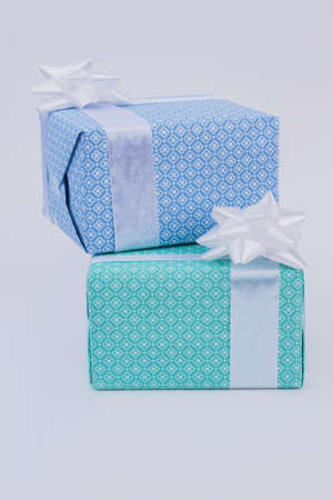 Two gift boxes wrapped in beautiful paper. Presents in boxes tied with bow, side view. Festive...