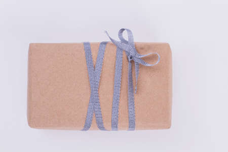Gift box wrapped in craft paper. Present box packed in brown vintage paper and tied with silver...