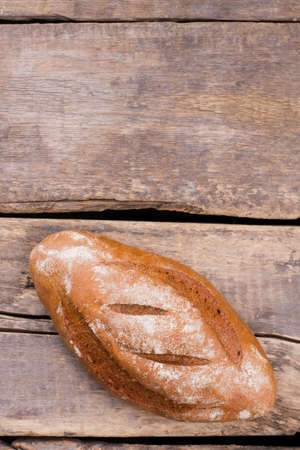 Loaf of fresh bread on vintage background. Top view of homemade organic bread on wooden planks. Copy...