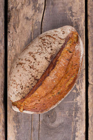 Loaf of fresh bread on wooden background, top view. Delicious homemade bread on old wooden table.