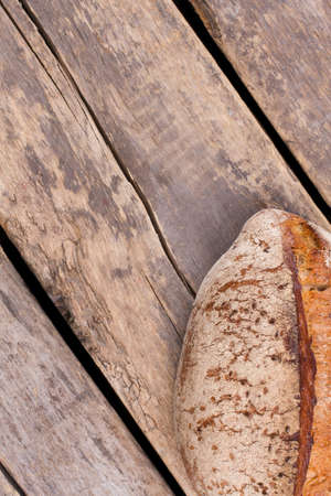 Loaf of homemade bread on rustic wooden background. Healthy wheat bread on cracked wooden boards....