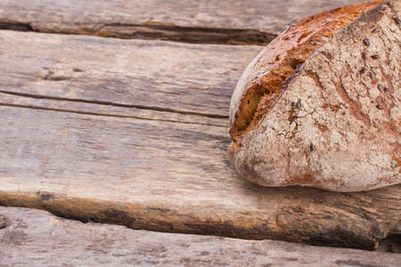 Homemade rustic bread loaf. Delicious crispy bread on vintage wooden background. Space for text.