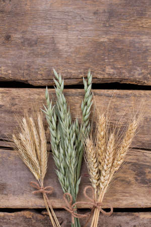 Cereal ears on wooden boards background. Oat, wheat and barley ears on old wooden floor. Space for text.の写真素材