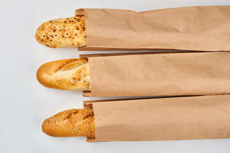 Set of fresh baguettes on white background. Three baguettes in kraft paper bags. Food at grocery.の写真素材