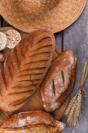 Bread and wheat ears on rustic table. Whole wheat bread and wheat spikelets on wooden background....