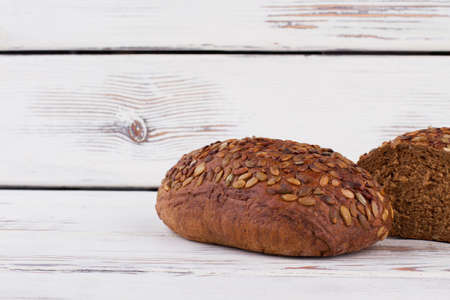 Rye bread with seeds on wooden background. Black bread with sunflower seeds. Health benefits of...