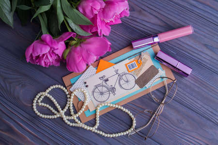 Lady's accessories flat lay. Peony flowers, lipstick, mascara, pearl necklace and abstract postcard collage.の写真素材