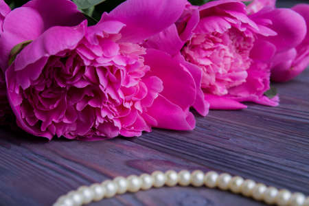 Close-up flowers peonies and pearl necklace. Gray wooden table surface.の写真素材