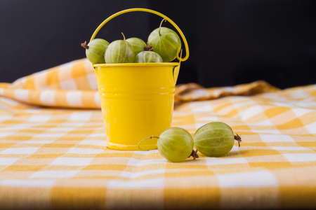 Yellow bucket of green cherry-cherry-plums. Black background.の写真素材