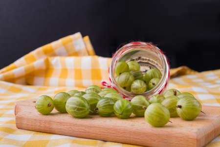 Many cherry-cherry-plums poured out of a jar. Wooden board for cooking.の写真素材