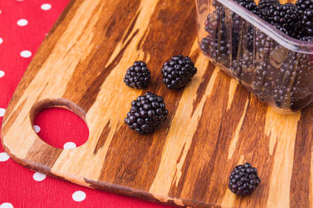 Blackberries prepared for cooking, close-up. Wooden rural kitchen board, harvest of berries in a...