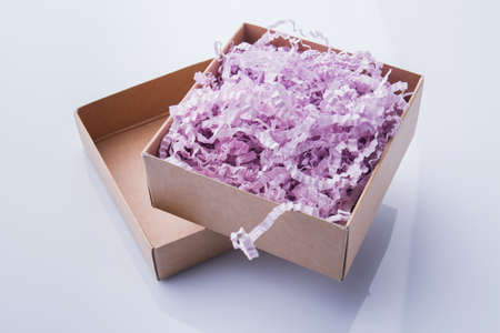 Opened two-piece box stuffed with colorful shredded paper. Isolated on white.の写真素材