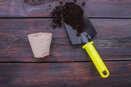 Trowel with soil and cardboard fibre cup. Dark wooden background.の写真素材
