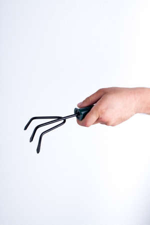 Garden fork rake close-up. Mans holding gardening tool. White isolated background.の写真素材