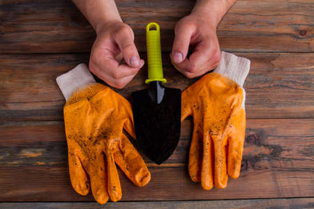 Pair of gloves, trowel and male's hands - gardening concept. Close-up, top view, flat lay.の写真素材