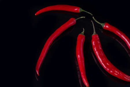 Chili peppers on black background. Red spicy vegetables. Food concept.
