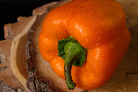 Orange sweet pepper close up. Crunchy capsicum on wooden cut. Food concept.の写真素材