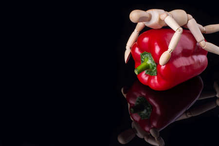 Wooden dummy hugs a pepper. Vegetarian love.