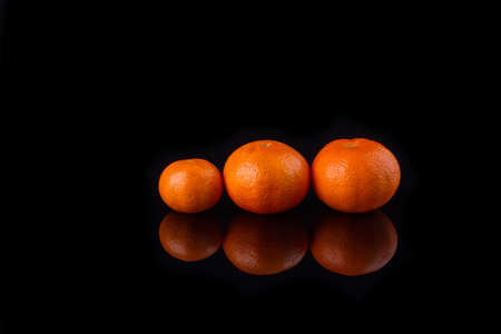 Tangerine row. Three ripe fruits.
