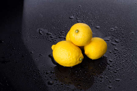 Yellow lemons in black studio. Citrus fruits are good for immunity.