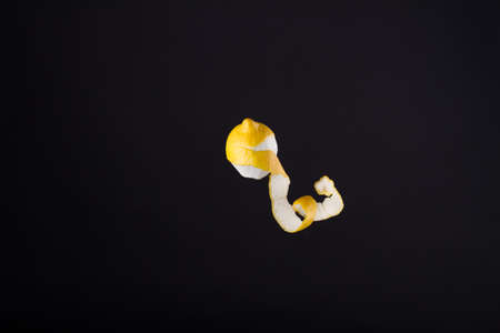 Peeled lemon hovering in the air. Yellow citrus with waving peel. Food concept.