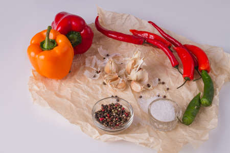Mix of peppers, garlic and condiments. Coarse salt in shaker. Parchment paper as a background.の写真素材