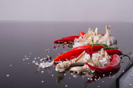 Hot chili and condiments in focus. Scarlet pepper with coarse salt. Food concept.