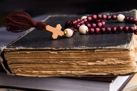 Christian faith symbol and bible. Wooden rosary with a cross lie on several ancient books.の写真素材