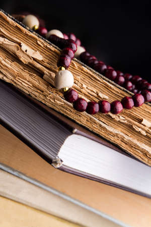Red wood rosary beads on old holy books. Close-up.