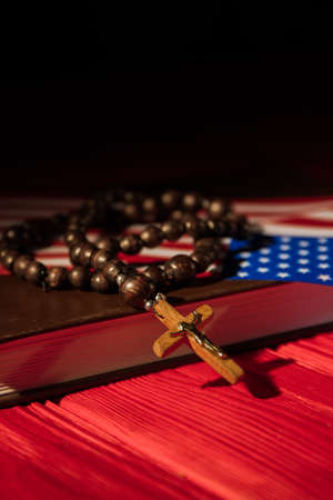 In God We Trust concept. Rosary with cross crucifix ans usa flag on holy bible book.の写真素材