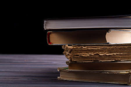 Stack of new and old books on wooden table. Black background.の写真素材