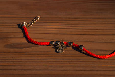 Red untied bracelete. Bracelete on brown wooden background.の写真素材