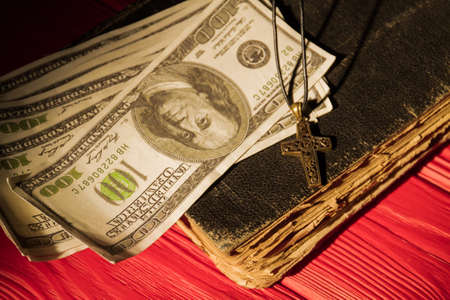 Money and religion prayer necklace with cross. Very old obsolete holy bible book.の写真素材