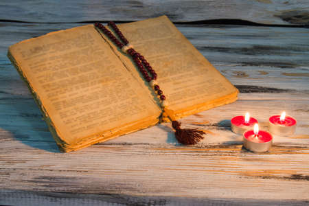 Open bible with rosary candles. Reading manuscript concept. Small candles with red wax.の写真素材