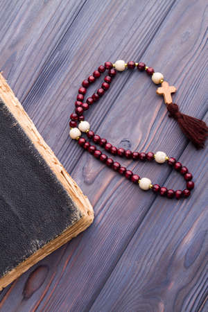 Faith and hope concept. Very old worn holy bible and rosary on wood.
