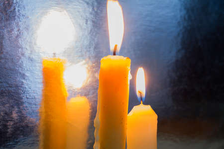 Two burning candles and their reflection. Light in front on a mirror.
