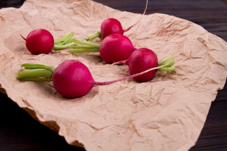 Close-up bunch of whole red radishes. Group of round vegetables on crumpled brown paper.の写真素材