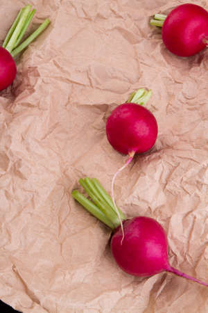 Red radishes on crumpled brown paper. Shiny vegetables, top view.の写真素材