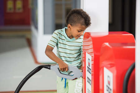 Gas station play set. Little boy having fun in amusement park. Entertainment and educational center for kids.の写真素材