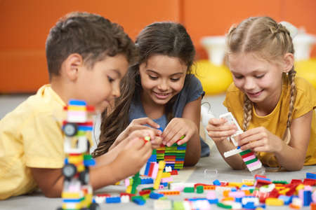 Happy kids playing with constructor at kindergarten. Children playing with colorful plastic bricks...
