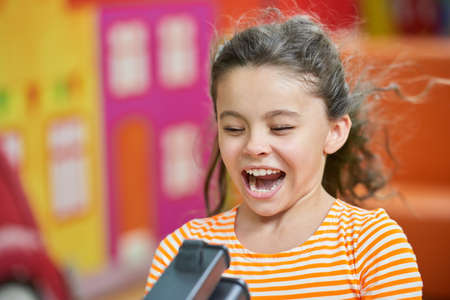 Joyful kid having fun on Birthday celebration. Funny little girl in entertainment center. Kids...