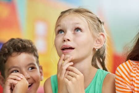 Pensive child looking up. Beautiful little girl looking thoughtful. Kids in play room.