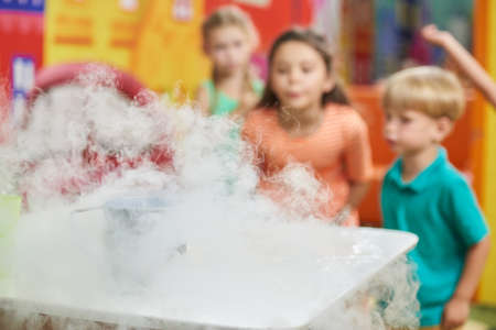 Experiment with dry ice at kids Birthday party. Dry ice smoke cloud in kids playroom. Scientific show for children.の写真素材