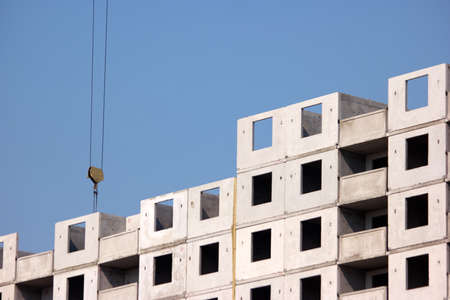 Concrete building structure. Crane planting concrete blocks, blue sky background.の写真素材