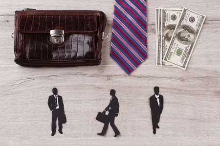 Attributes of clerk. Purse, tie and dollar bills. Paper mens figures.