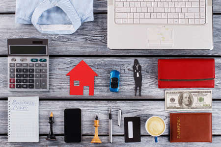 Mini car, paper house and womes silhouette in center. Stuff of successful businesswoman. Personal items around.の写真素材